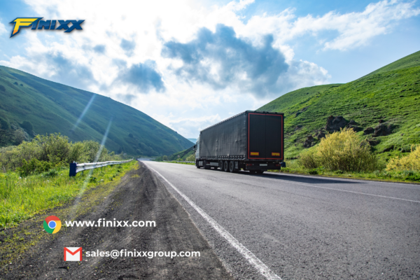 A truck driving on a scenic highway with green hills in the background, representing Finixx Tyre’s durable and reliable truck tires for global trade